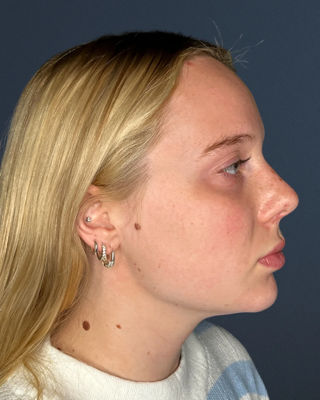 A profile photo of a young blonde woman against a dark blue background.