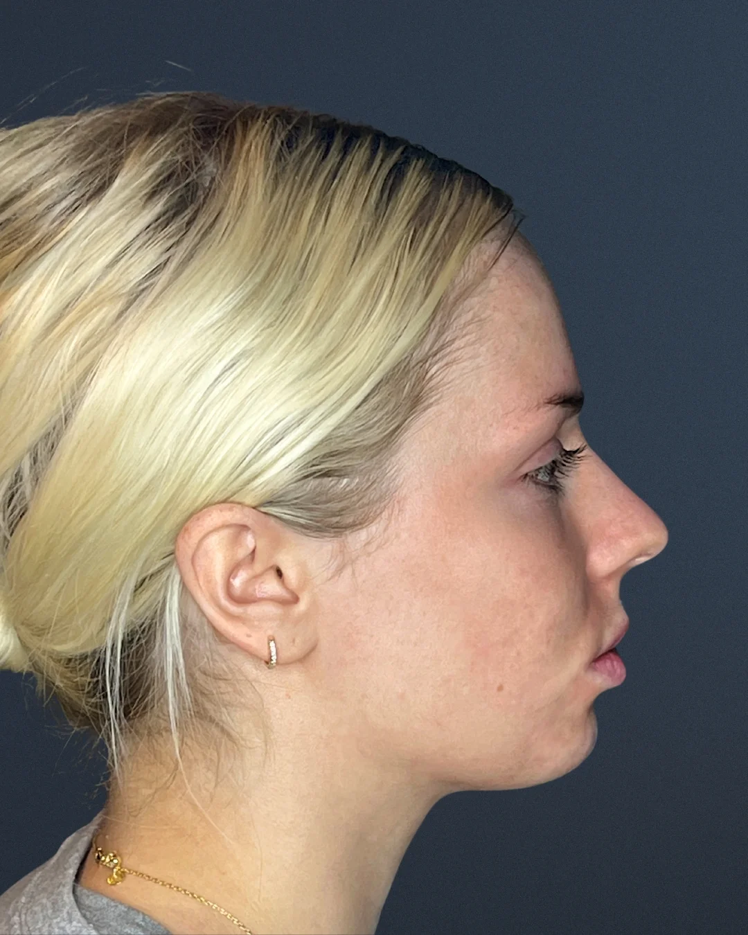 A profile photo of a young blonde woman against a dark blue background.