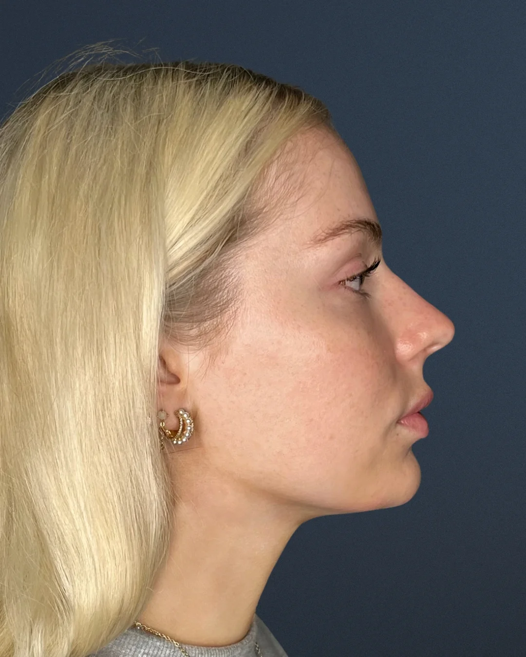A profile photo of a young blonde woman against a dark blue background.