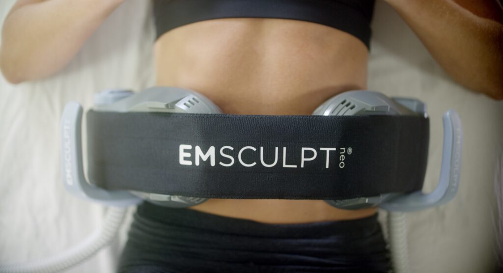 A woman's abdomen with an Emsculpt Neo device attached.