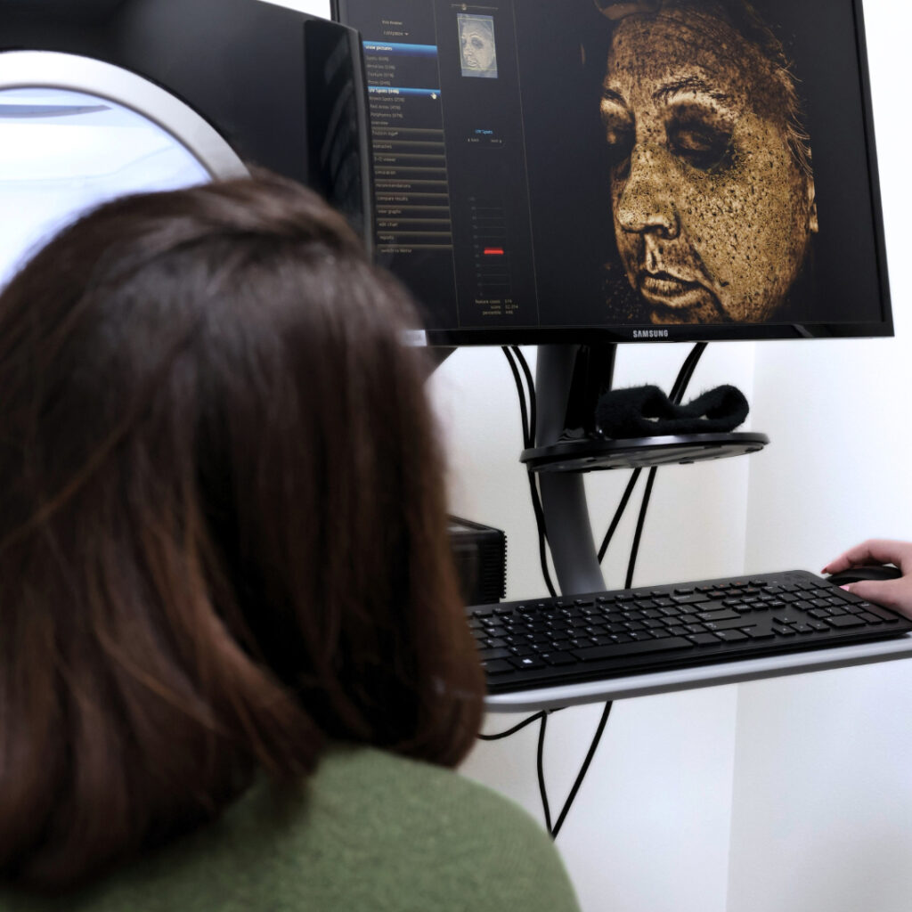 A technician and patient review the results of a Skin Visia scan.