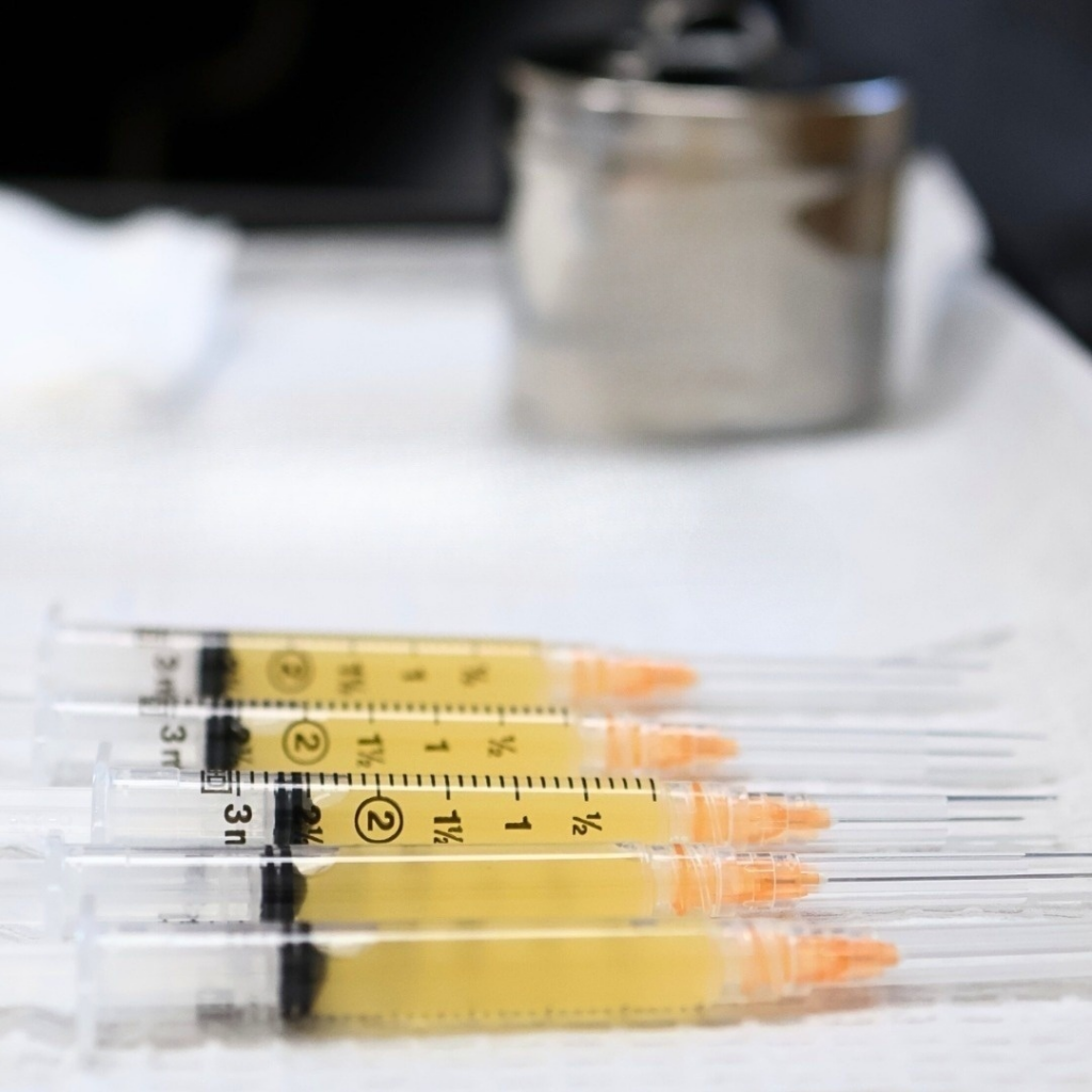 Several medical syringes lined up, each filled with a yellow liquid.